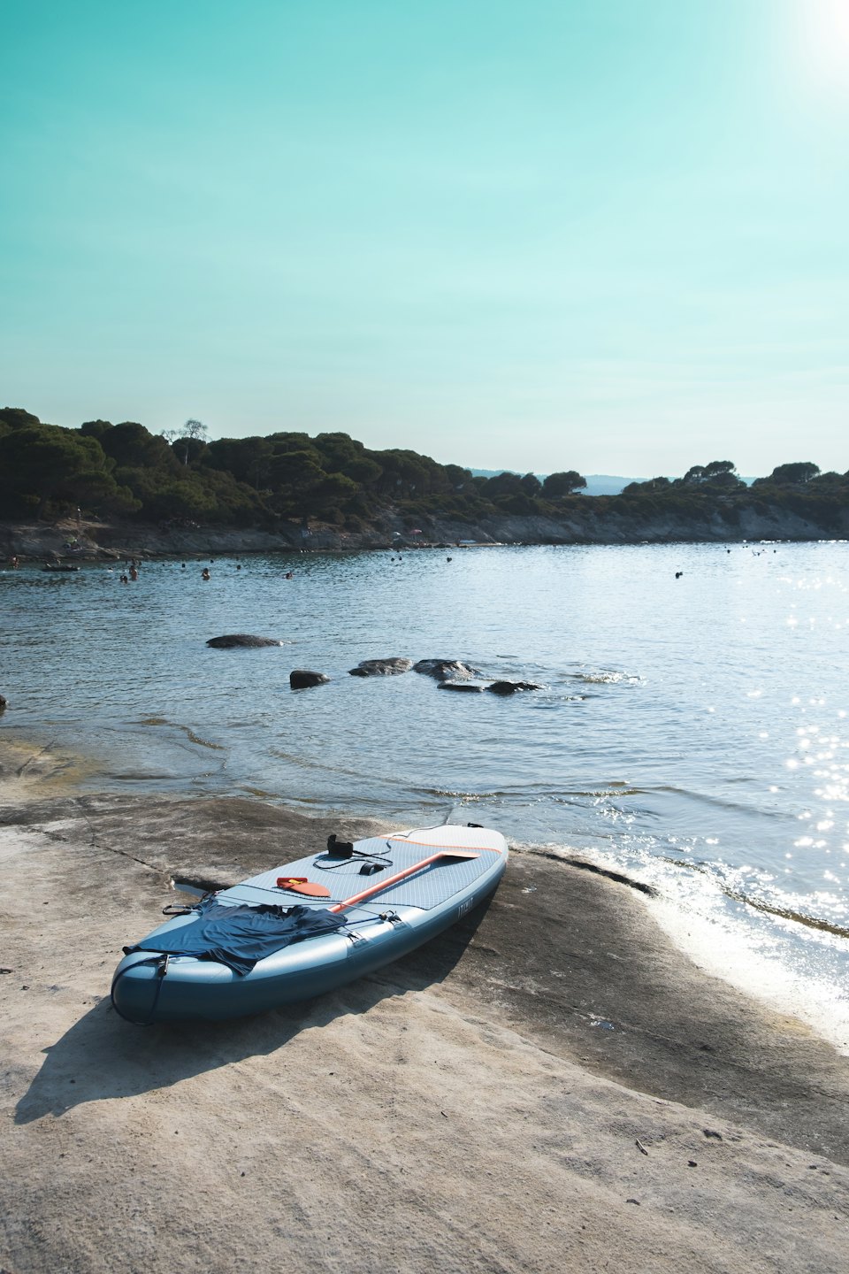 Tavola da SUP con pagaia e maglietta su una spiaggia.