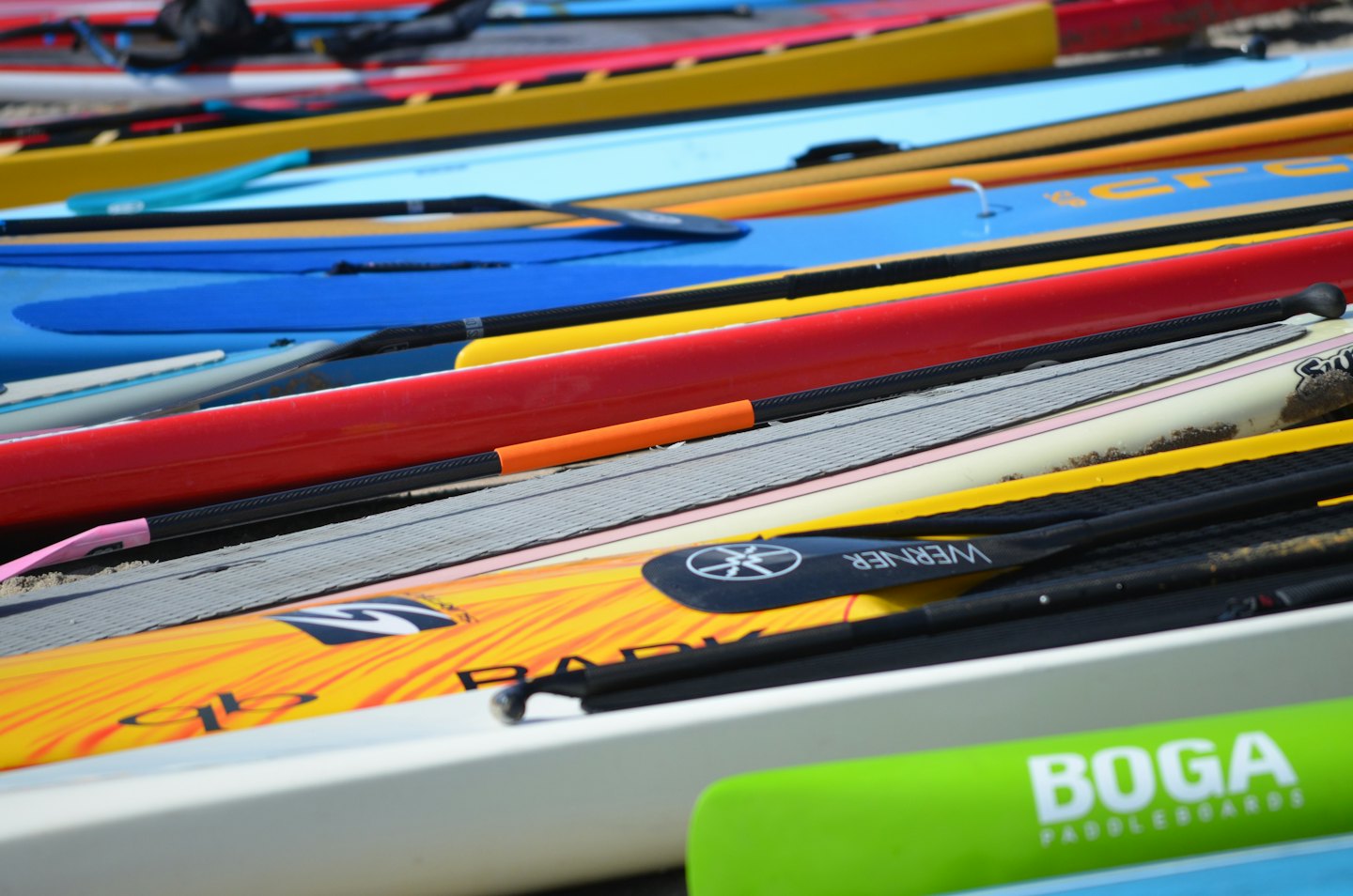 Tavole da paddleboard colorate impilate su un molo di legno.