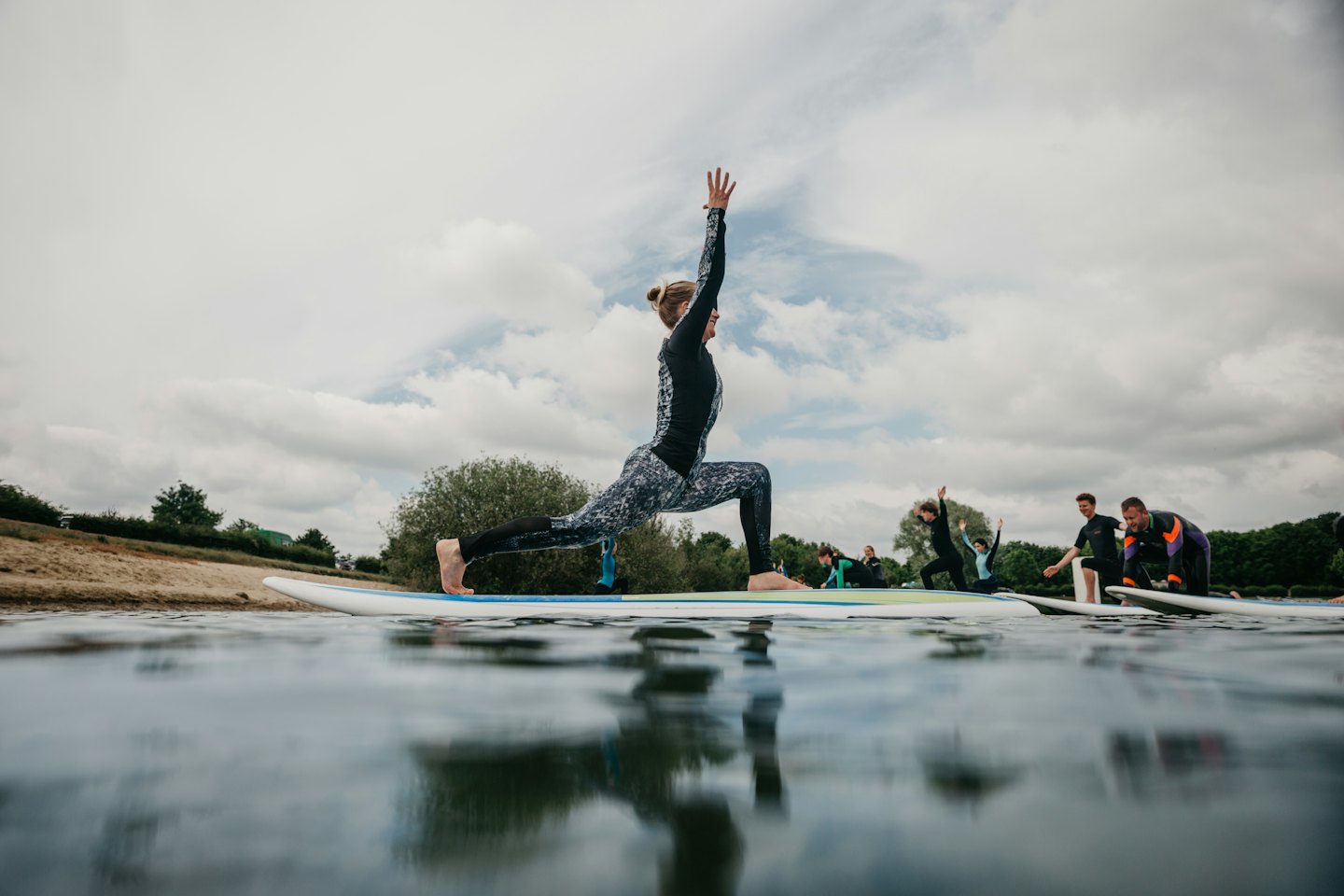 Donna in posizione di affondo yoga su una tavola da paddle sul lago.